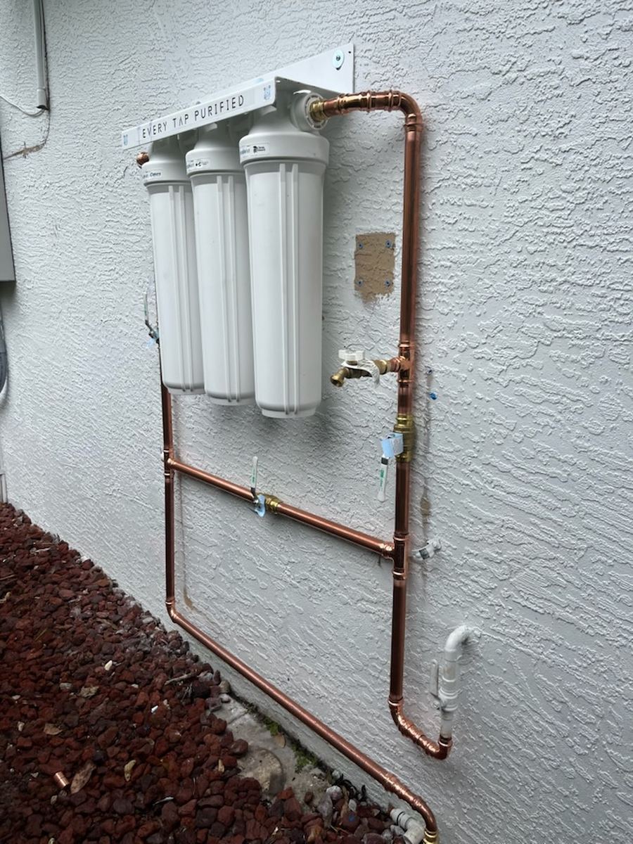 Close-up of a whole-home water filtration system with copper bypass piping